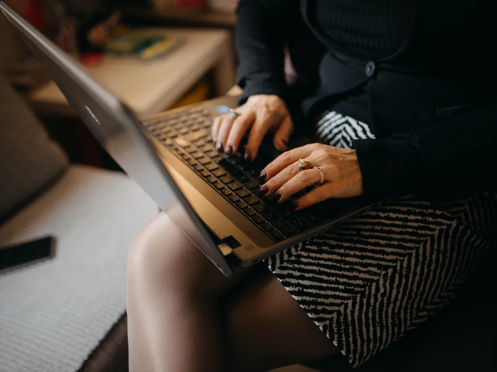 A person focused on a laptop while working from home at a desk